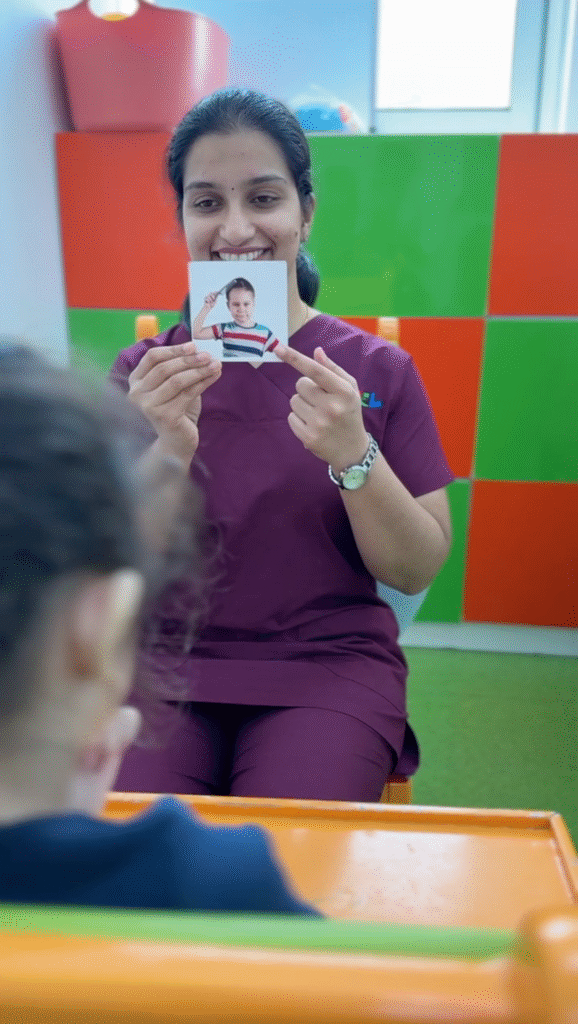 A speech therapist showing an emotion flashcard to a child during a therapy session at the best speech therapy center in Dubai.